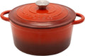 A red-orange enameled cast iron Dutch oven with a matching lid and silver knob, featuring side handles and the 'le creole' brand name embossed on the lid.