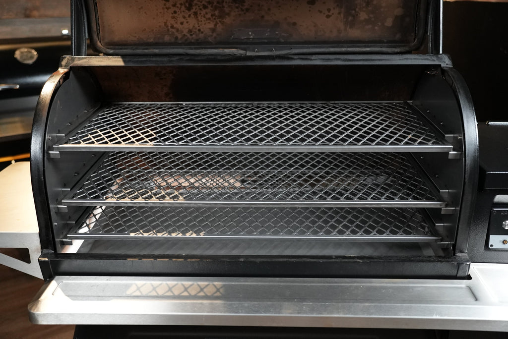 Open grill with two mesh racks inside, showing signs of use.
