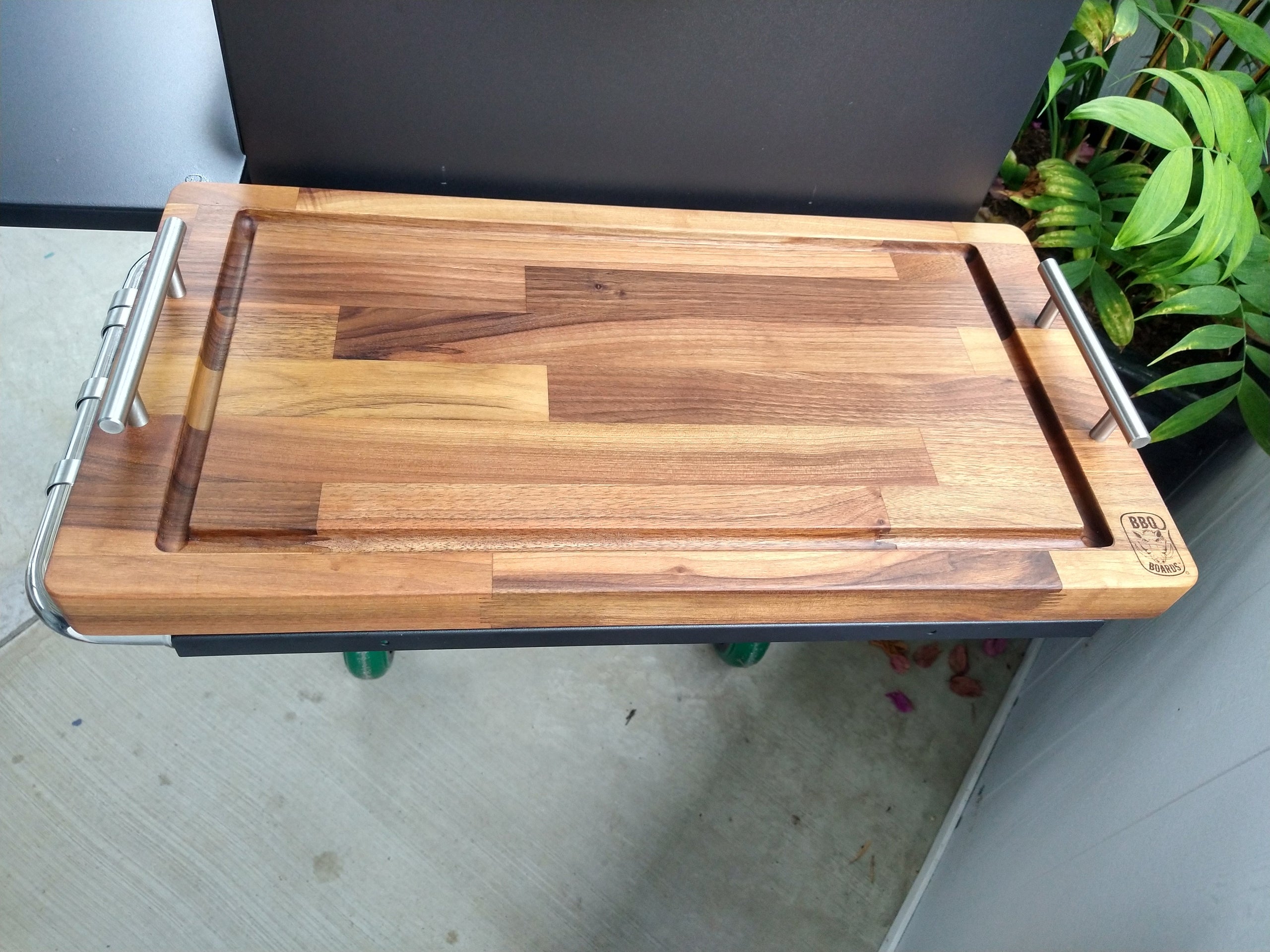 Wooden cutting board on a stand with a plant in the background
