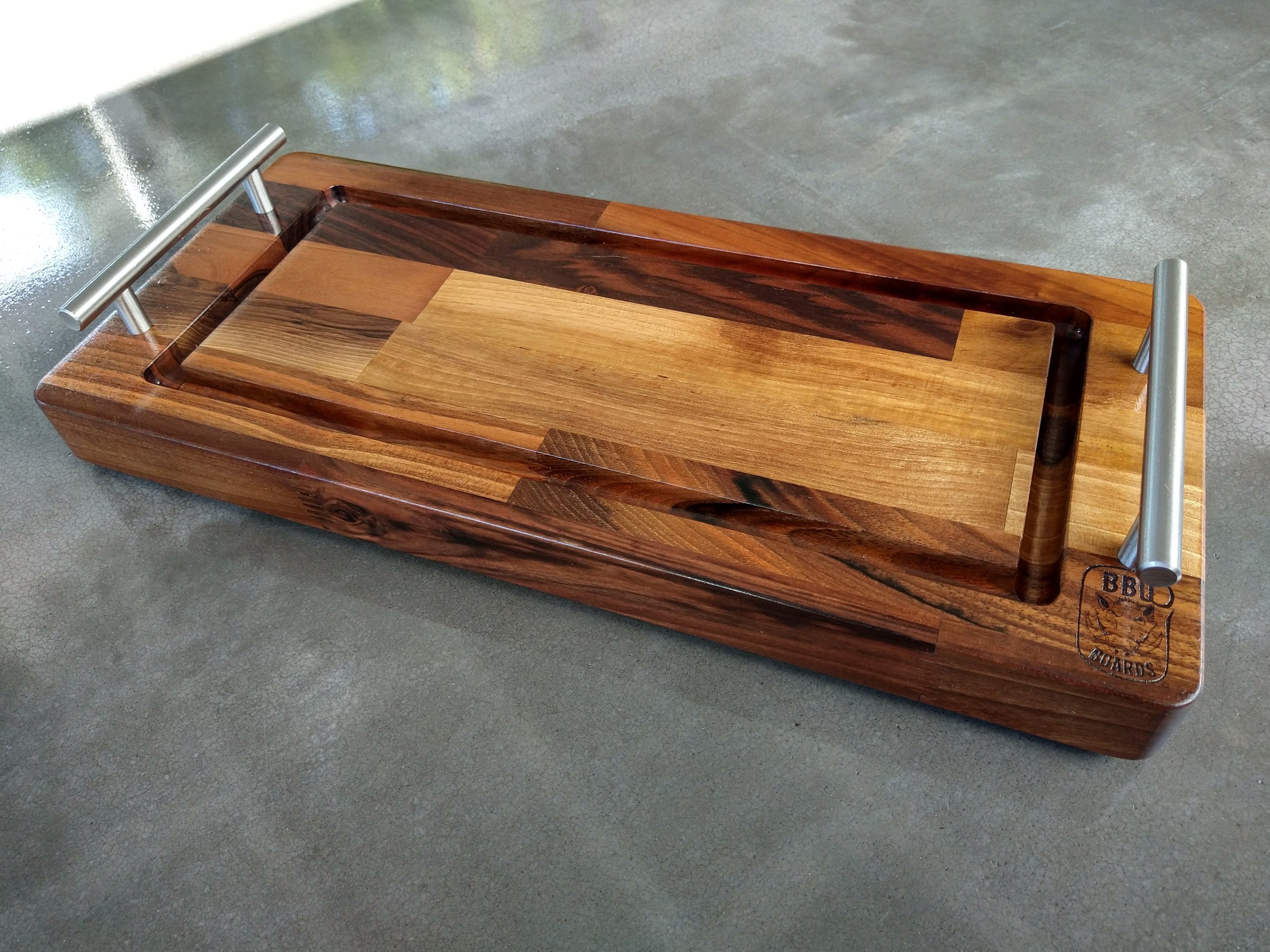 Wooden cutting board with metal handles on a gray surface